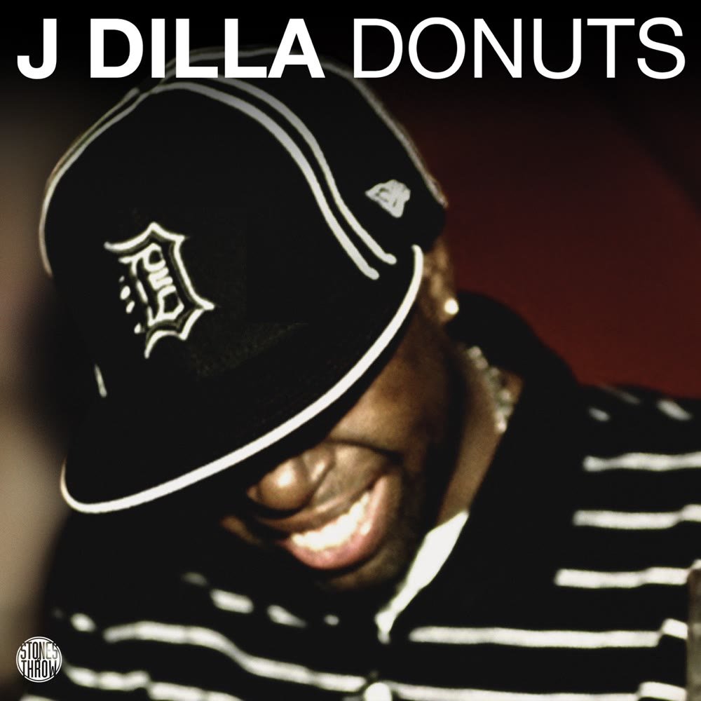 Donuts album cover: J Dilla smiling under a Detroit baseball cap, wearing a striped shirt