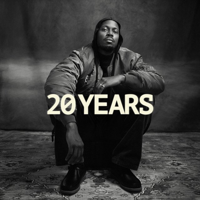 20 Years single cover: Illa J crouching in a hoodie and jacket in a black and white photo, with the title in white letters