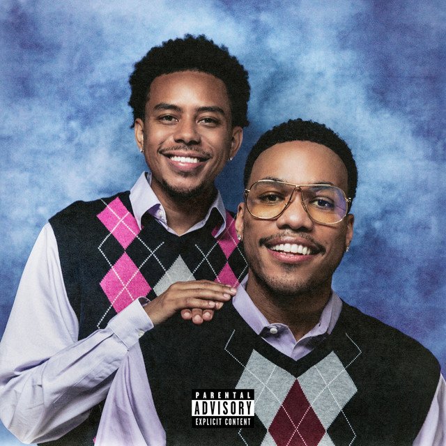 Heavy Is The Crown album cover: Cordae and Anderson .Paak smiling in matching argyle sweater vests, in an old-school portrait studio photo