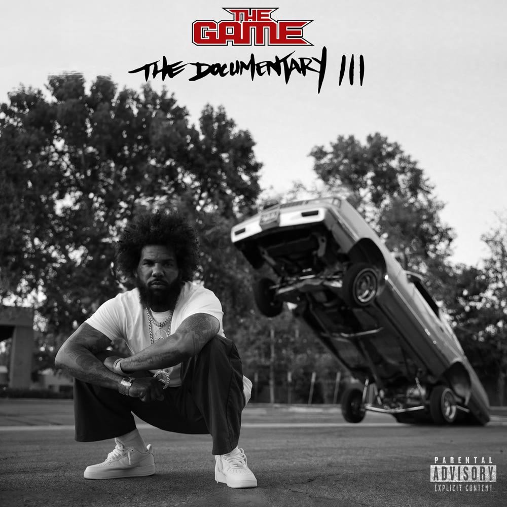 The Documentary III album cover: The Game crouching on the street in black and white while a lowrider car hops on three wheels behind him